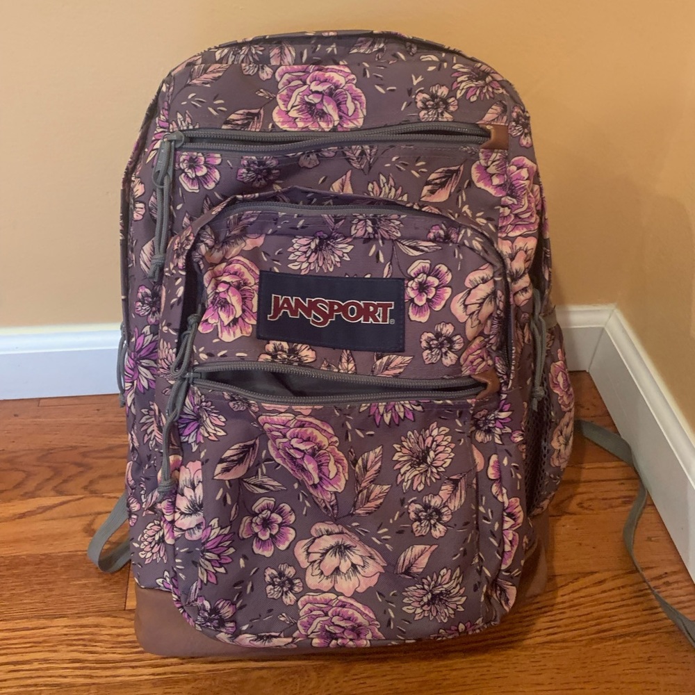 JanSport Cool Student floral backpack with synthetic leather base and trim.